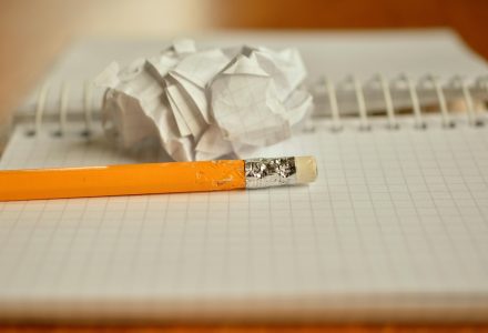 纸质记录本摊开在木桌上，页面上用铅笔写着检索关键词与选集逻辑的草稿，旁边放着一杯已经凉掉的茶，透出内容整理的耐心